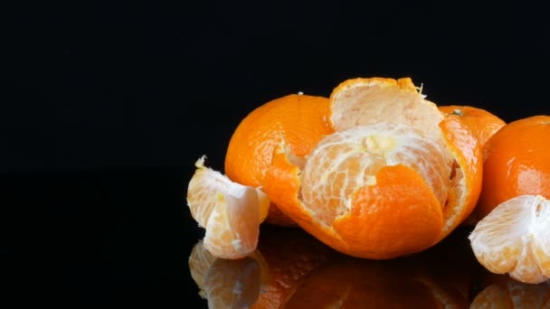 Rijpe sinaasappel mandarijnen op een spiegeloppervlak op een zwarte achtergrond. — Stockvideo