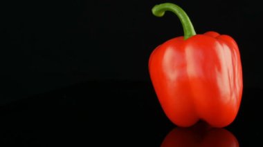 Ayna yüzeyi ve siyah arka planda dönen güzel büyük Olgun kırmızı tatlı biber Paprika.