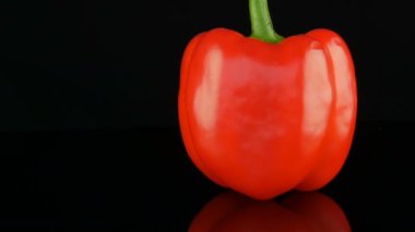 Ayna yüzeyi ve siyah arka planda dönen güzel büyük Olgun kırmızı tatlı biber Paprika.
