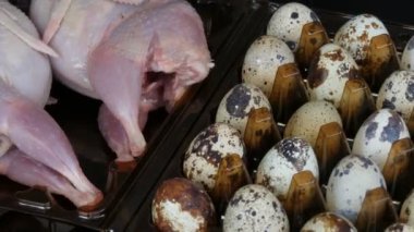 Siyah bir arka planda bıldırcın yumurtalarının yanında plastik kahverengi bir tepsi içinde bıldırcın taze et.