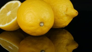 Siyah arka planda siyah ayna yüzeyinde büyük taze sarı limon görünümü yakın.