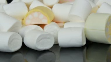 Ayna yüzeyi ve siyah arka planda yavaş renkli mini Marshmallow şekerler rotasyon. Diyabet sorunu ve tatlı aşırı yeme.