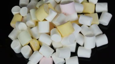 Ayna yüzeyi ve siyah arka planda yavaş renkli mini Marshmallow şekerler rotasyon. Diyabet sorunu ve tatlı aşırı yeme.