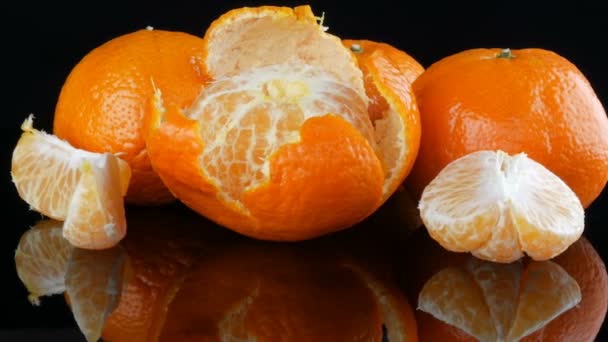 Mandarines orange mûres sur une surface miroir sur un fond noir . — Video