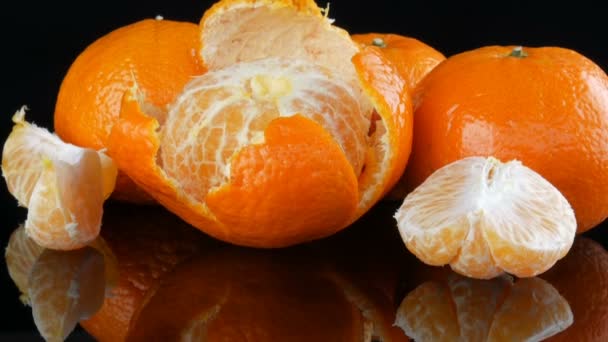 Rijpe sinaasappel mandarijnen op een spiegeloppervlak op een zwarte achtergrond. — Stockvideo