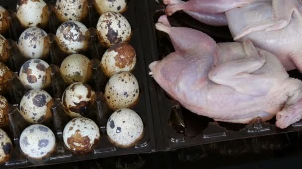 Carne fresca de codorniz en una bandeja de plástico marrón junto a los huevos de codorniz sobre un fondo negro . — Vídeos de Stock