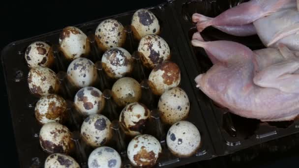 Daging segar burung puyuh di nampan plastik coklat di sebelah telur burung puyuh di latar belakang hitam . — Stok Video