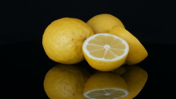 Grandes limones amarillos frescos en la superficie del espejo negro sobre un fondo negro . — Vídeo de stock