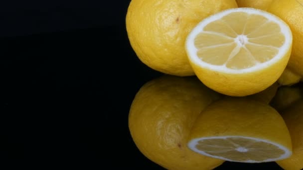 Grandes limones amarillos frescos en la superficie del espejo negro sobre un fondo negro vista de cerca . — Vídeo de stock