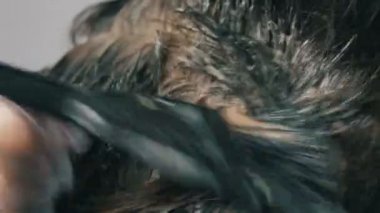 Özel fırça ile saçlarını kendi renklendiren orta yaşlı bir kadının büyümüş gri kökleri. Beyaz bir arka planda bir kadınların kafası koyu saçlı ve beyaz kökleri. Salon yakın görünüm saç bakımı.