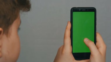 Genç oğlan beyaz arka planda yeşil bir ekran ile el Siyah bir smartphone tutar. Teknoloji