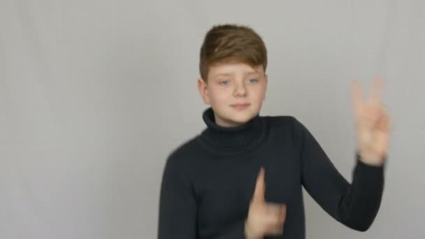 Portrait of a funny blond and blue-eyed teenager boy Funny and fun dancing in front of the camera on white background. Emotions of teenagers — Stock Video