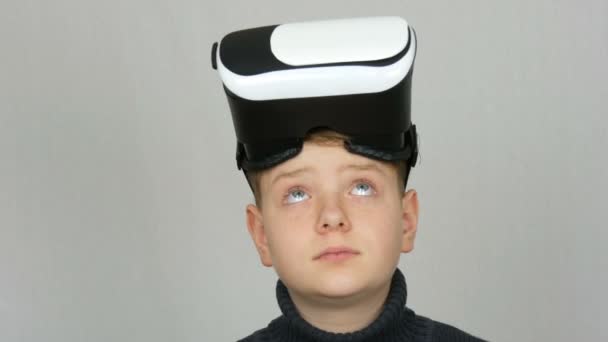 Хлопчик-підліток з віртуальною реальністю або окулярами vr на голові і розважається на білому тлі в студії — стокове відео