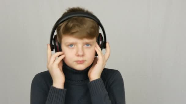 Funny tiener jongen in grote koptelefoon op zijn hoofd is het luisteren naar muziek, dansen en plezier op een witte achtergrond in de Studio — Stockvideo