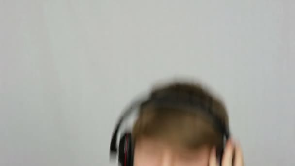 Zabawny nastolatek chłopiec w dużych słuchawkach na głowie jest słuchanie muzyki, taniec i zabawy na białym tle w Studio — Wideo stockowe