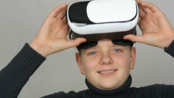 Adolescente chico con realidad virtual o gafas VR en la cabeza y divertirse en un fondo blanco en el estudio — Vídeos de Stock