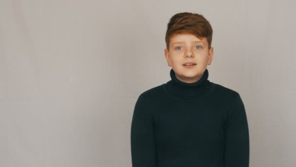Komik kızıl ve mavi gözlü genç çocuk portresi. Bir röportaj verir ve beyaz bir arka planda kamera tarafından utanıyor. Gençlerin duyguları — Stok video