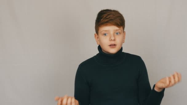 Portrait d'un adolescent rousse drôle et aux yeux bleus montrant la condamnation avec des gestes et des expressions faciales sur fond blanc. Les émotions des adolescents — Video