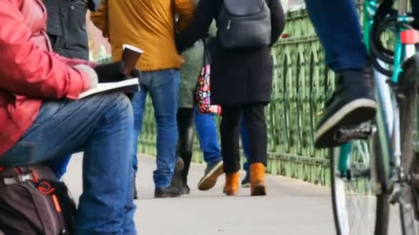 Budapest, Ungern-December 6, 2018: en hungrig tiggare sitter på asfalten av bron, har en allmosor kopp, och läser bok, människor förbi, en förbipasserande cyklist ger allm — Stockvideo