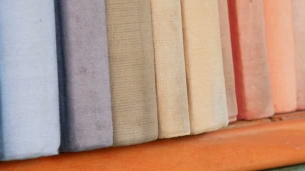Rij van grote oude multi-gekleurde boeken op een boekenplank in bibliotheek. — Stockvideo