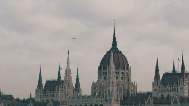 Den världs berömda parlamentsbyggnaden i Budapest byggdes i det gotiska i bakgrunden av ett flyg plan flyger uppifrån i molnigt väder. — Stockvideo