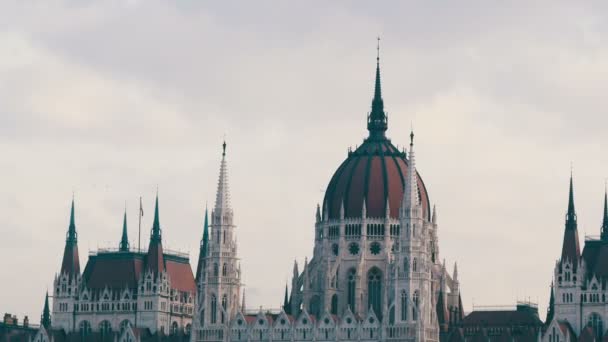 Den världs berömda parlamentsbyggnaden i Budapest byggdes i det gotiska i bakgrunden av ett flyg plan flyger uppifrån i molnigt väder. — Stockvideo