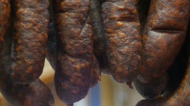 Una fila de salchichas ahumadas cuelgan de la vitrina de una carnicería — Vídeos de Stock