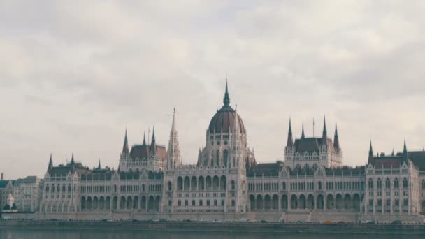 Den världs berömda parlamentsbyggnaden i Budapest byggdes i det gotiska i bakgrunden av ett flyg plan flyger uppifrån i molnigt väder. — Stockvideo