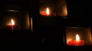 Bir Katolik kilisenin karanlığında özel bir niş içinde güzel kırmızı yuvarlak dua mumlar yakma.
