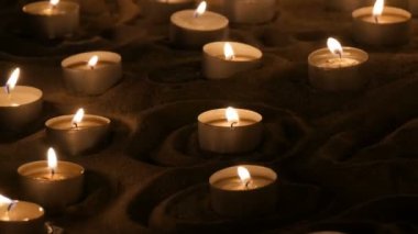 Kum yanan küçük beyaz yuvarlak mumlar çok sayıda. Balmumu mumlar yanan arka plan.