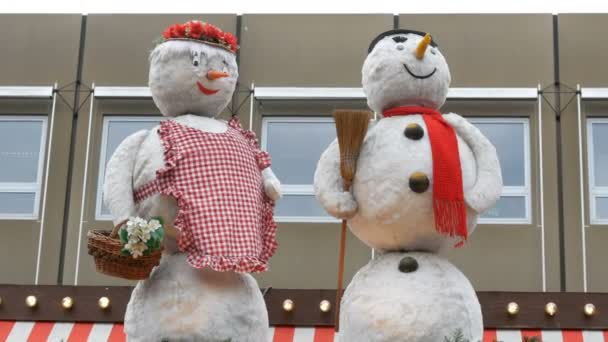 ヨーロッパの子供のクリスマスマーケットのキオスクの屋根の上に雪だるま人形を移動. — ストック動画