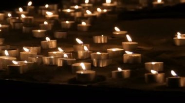 Kum yanan küçük beyaz yuvarlak mumlar çok sayıda. Balmumu mumlar yanan arka plan.