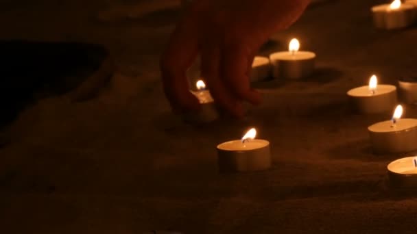 Een groot aantal kleine witte ronde kaarsen branden in het zand. Achtergrond van brandende Wax kaarsen. — Stockvideo