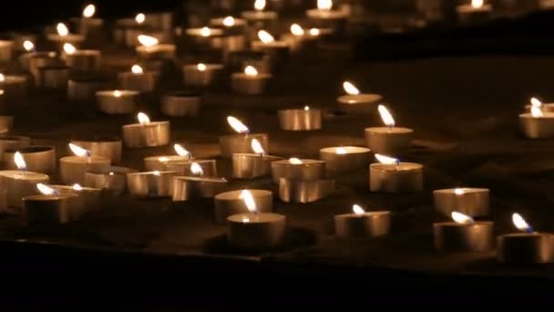 Um grande número de pequenas velas redondas brancas queimando na areia. Fundo de velas de cera ardente . — Vídeo de Stock