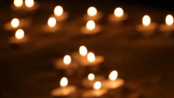 Muitas belas velas brancas borradas, redondas e pequenas queimando na areia no escuro . — Vídeo de Stock