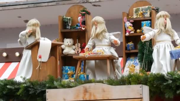 Drie bewegende engelen poppen zijn verpakking presenteert in Snow-White jurken op het dak van een kiosk van de Childrens kerstmarkt in Europa. — Stockvideo