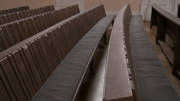 Insida en tom katolsk kyrka. Trä bänk för församlings medlemmar. — Stockvideo