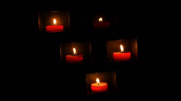Quemando hermosas velas redondas rojas de oración en un nicho especial en la oscuridad de una iglesia católica . — Vídeo de stock