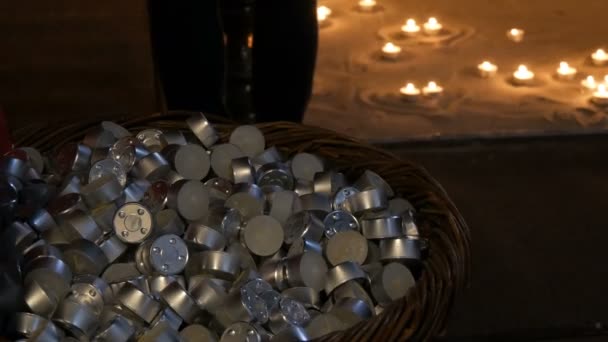 A large number of small round wax candles that lie in a large pile in the background burning candles. — Stock Video