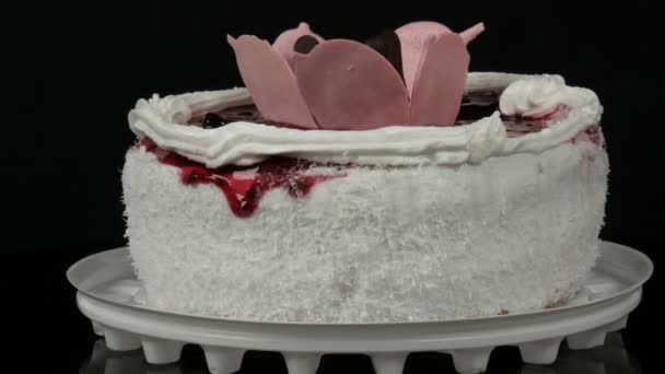 Beautiful stylish sweet fresh white cake with cherry jam decorated on top with cream and coconut chips on a black background. — Stock Video