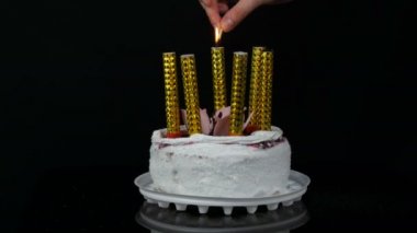 Womens üzerinde krem ve Hindistan cevizi gevreği ile süslenmiş kiraz reçel ile güzel bir şık tatlı taze beyaz kek üzerinde hafif mumlar eller. Siyah arka planda Doğum günü pastası.