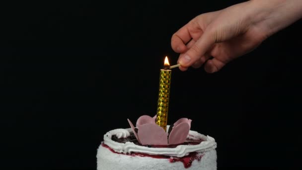 As mãos das mulheres acendem velas em um belo bolo branco doce e elegante com geléia de cereja decorada com creme e flocos de coco no topo. Bolo de aniversário no fundo preto . — Vídeo de Stock