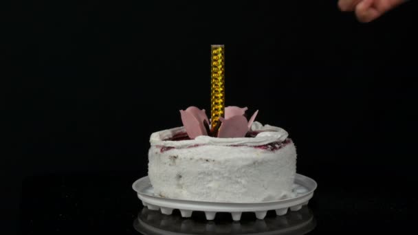 Las manos de las mujeres encienden la vela en un hermoso pastel blanco dulce y elegante con mermelada de cereza decorada con crema y copos de coco en la parte superior. Tarta de cumpleaños sobre fondo negro . — Vídeo de stock