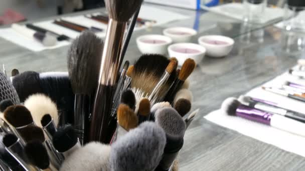 Set di spazzole professionali per il trucco sul tavolo nello spogliatoio. Industria della moda. Sfilata di alta moda dietro le quinte. Truccatore prende un pennello . — Video Stock