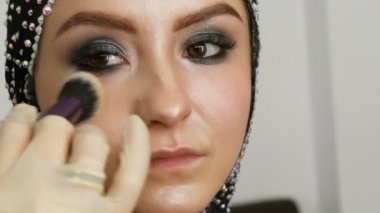 Profesyonel fırça ile blendable vurgu modeli yakın yukarı yüzüne uygulanır. Stüdyoda güzel kahverengi gözleri ile genç kız modeli. Profesyonel makyaj yüksek moda makyaj sanatçısı
