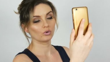 Bir akıllı telefonda bir selfie alır ve beyaz bir arka plana karşı kendini hayran siyah bir elbise güzel bir genç seksi zarif kadın portre