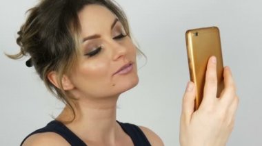 Bir akıllı telefonda bir selfie alır ve beyaz bir arka plana karşı kendini hayran siyah bir elbise güzel bir genç seksi zarif kadın portre