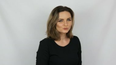 Güzel genç seksi şık elbiseli bir kadın funnyly gözleri söylüyorsun ve kameraya beyaz arka plan üzerinde gülümseyen bir siyah portresi.
