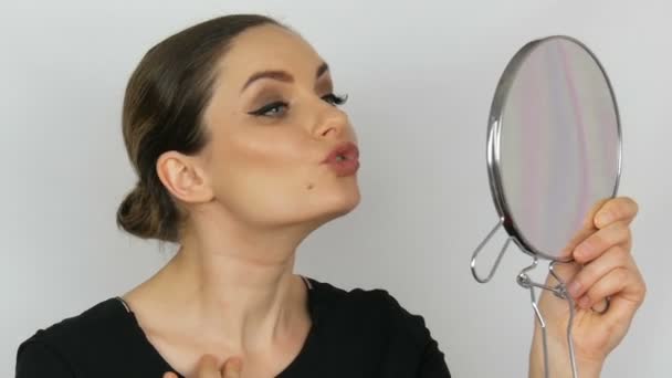Mooie elegante sexy jonge vrouw houden een ronde spiegel in haar handen en op zoek naar het bewonderen van zichzelf op een witte achtergrond. — Stockvideo