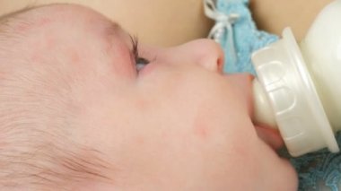 İki aylık bebek anne silah yatıyor ve bir meme süt şişeden berbat. Childs'ın yüz görünümü kapatın